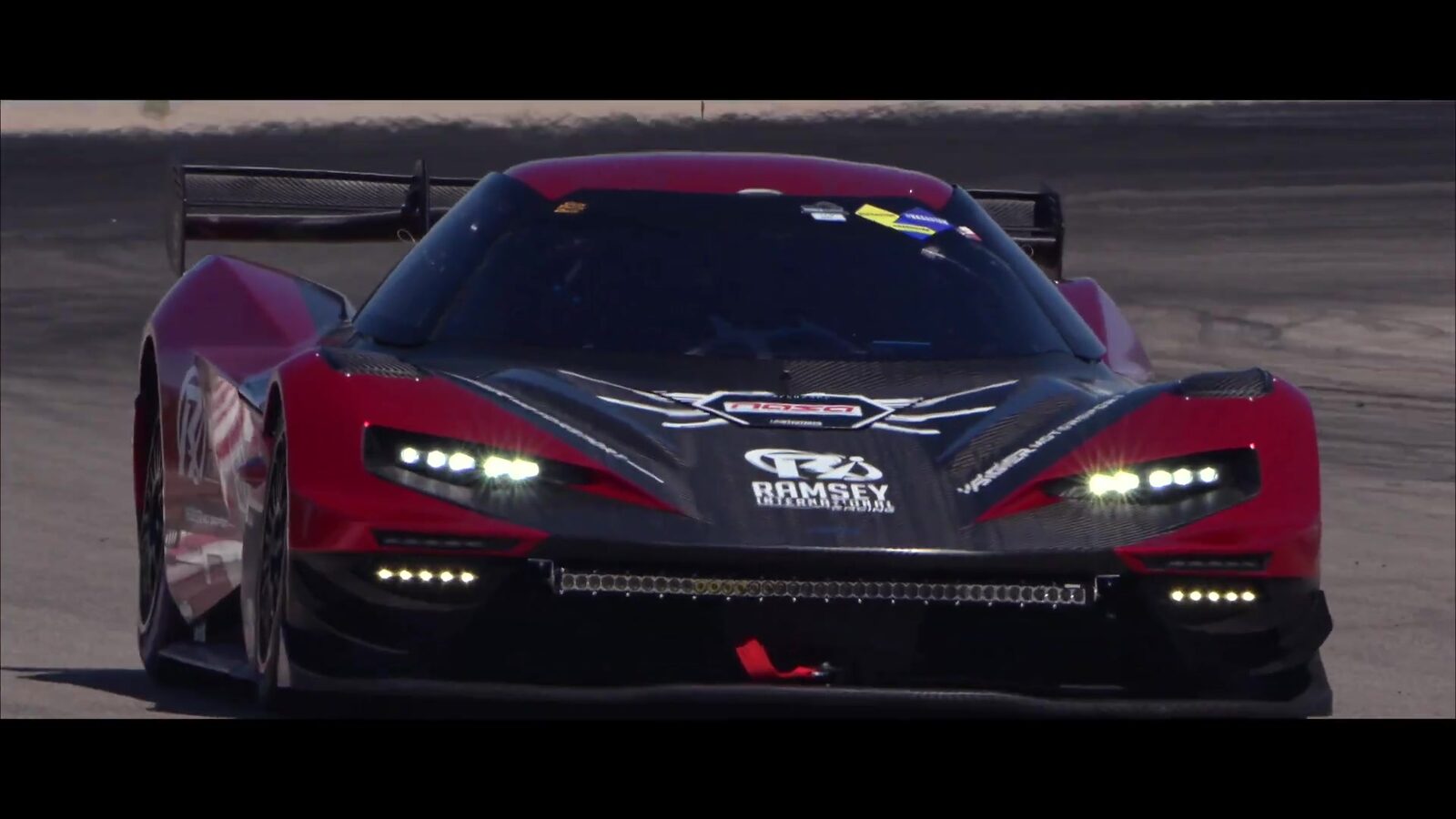 The Ramsey International KTM X-BOW GT2 head-on with its headlights lit, from the Driven As One trailer
